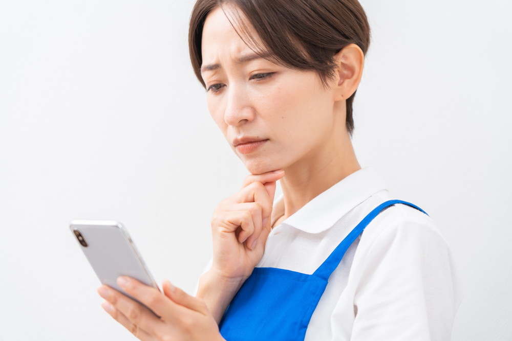 スマホを見つめて悩む女性